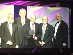 Roger Jette, center, accepts the Harry J. Pfister Award for Excellence in the Telecommunications Industry in January 2019.