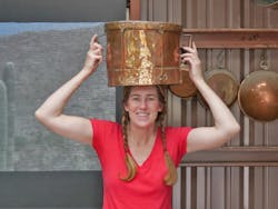 Val modeling an 18th century ferrat. French women used these tin-lined copper vessels to transport water from the public fountain on their heads.