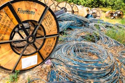 Chiang Mai/Thailand - April 17, 2019: Wooden and steel reels of black and blue telecommunication cables lying on the ground.