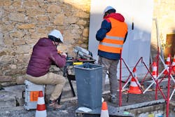 Technicians working on a street installing fiber-optics for a high speed internet network. Technicians working on a street installing fiber-optics for a high speed internet network.