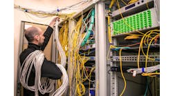 An ICT technician handling unruly cabling within a data center.