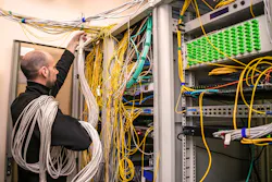 An ICT technician handling unruly cabling within a data center. An ICT technician handling unruly cabling within a data center.