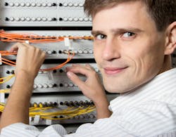 An engineer in an Internet Service Provider data center network maintains fiber-optic patch cords.
