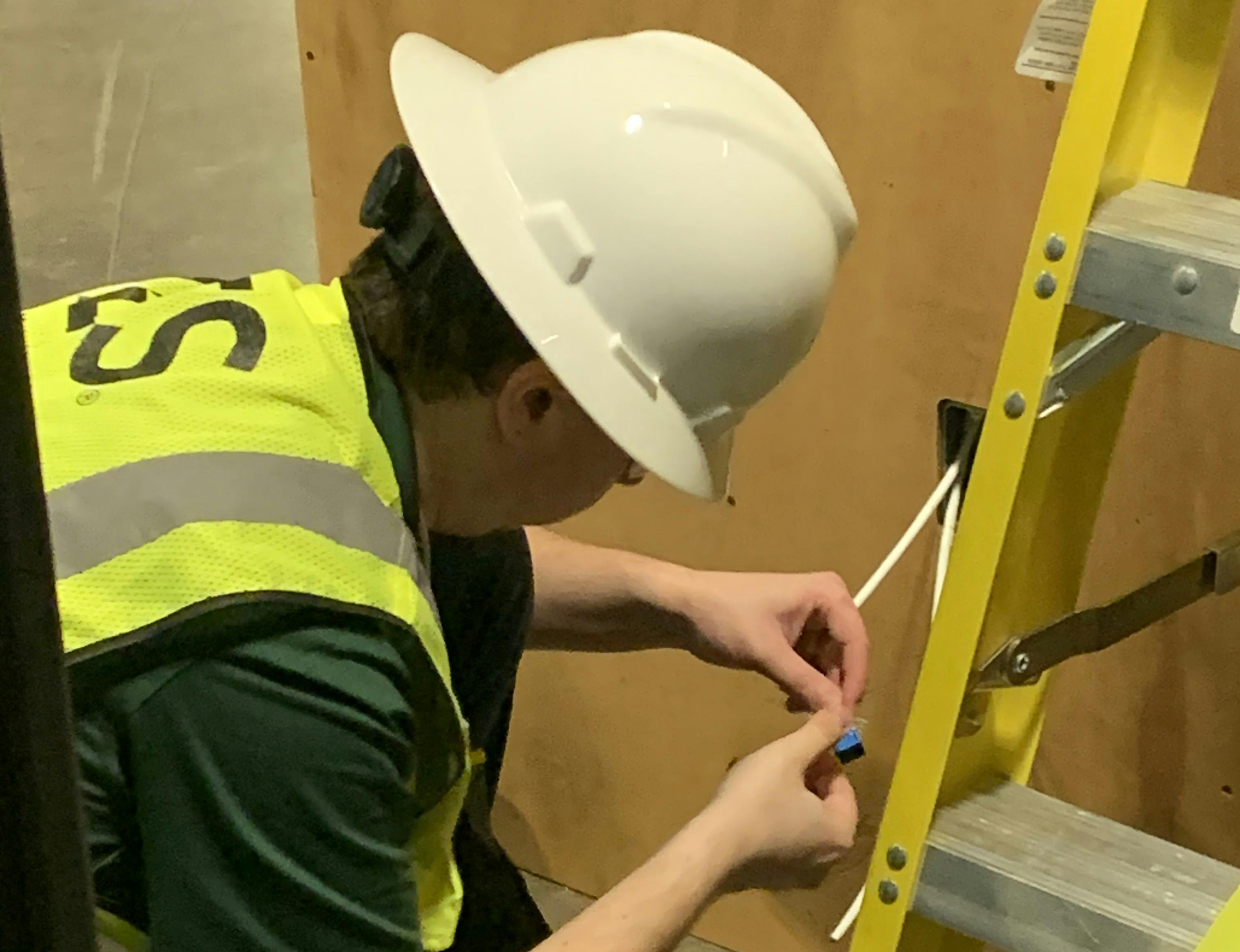 A competitor in the 2023 Cabling Skills Challenge terminates a Category 6A cable to a work-area outlet.
